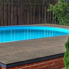 Ein Schwimmbecken wurde im Garten nicht ebenerdig, sondern etwa 50 cm erhöht eingebaut. Um das Becken herum wurde eine Terrasse angelegt. Der Beckenumlauf aus WARCO Schwimmbadplatten im Farbdesign Terrakotta schließt bündig mit der Oberkante des Schwimmbeckens ab.